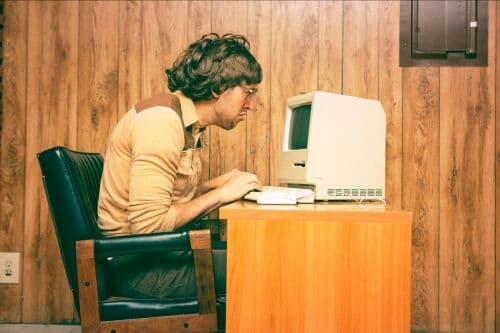 Muž u starého počítače v retro kanceláři