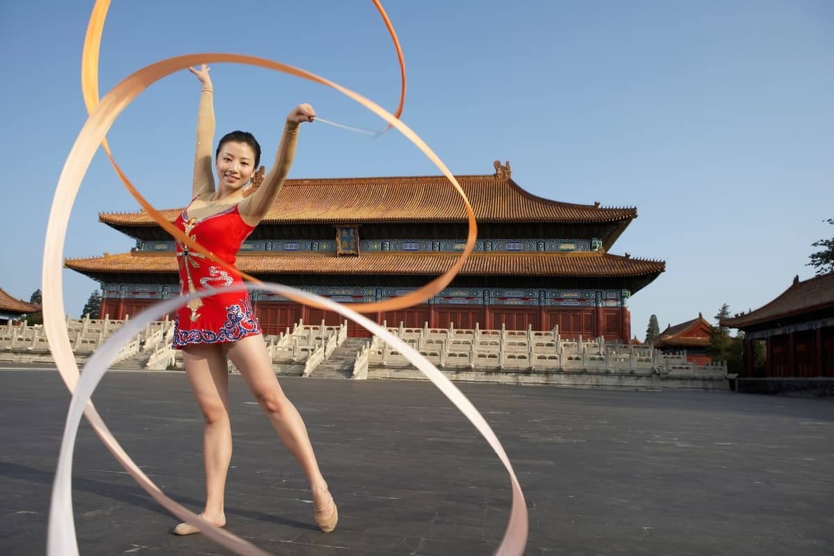 Rytmická gymnastka s páskou před Zakázaným městem v Pekingu